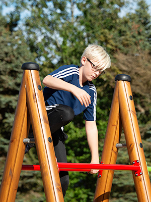 A young boy jumps over an obstacle course unit.